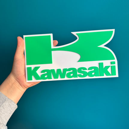 Logo Kawasaki en relief 3D, finition lisse et design fidèle.

