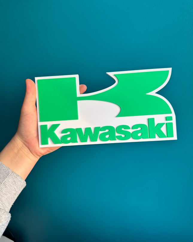 Logo Kawasaki en relief 3D, finition lisse et design fidèle.


